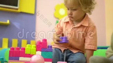 美丽的金发幼儿园可爱的幼儿玩多色积木在幼儿园。 儿童发展